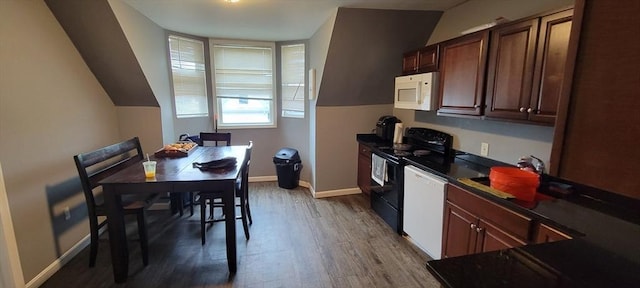 kitchen with white appliances, dark wood finished floors, dark countertops, vaulted ceiling, and baseboards