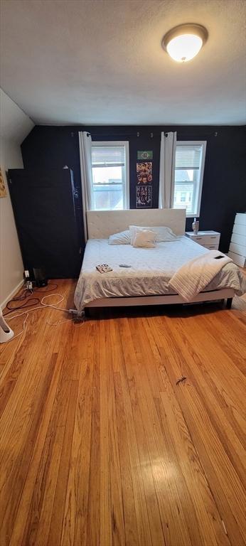 bedroom with wood finished floors, multiple windows, and vaulted ceiling