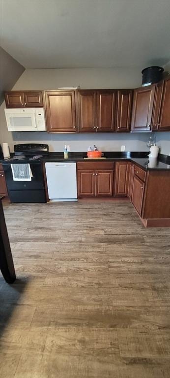 kitchen with white appliances, dark countertops, and light wood finished floors