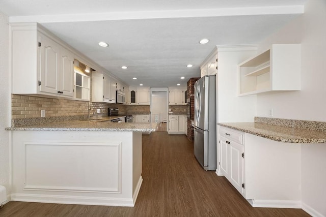 kitchen featuring appliances with stainless steel finishes, a peninsula, a sink, open shelves, and dark wood-style flooring