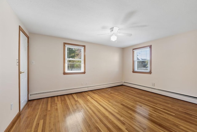 spare room with light wood-style flooring, ceiling fan, a baseboard radiator, and baseboards