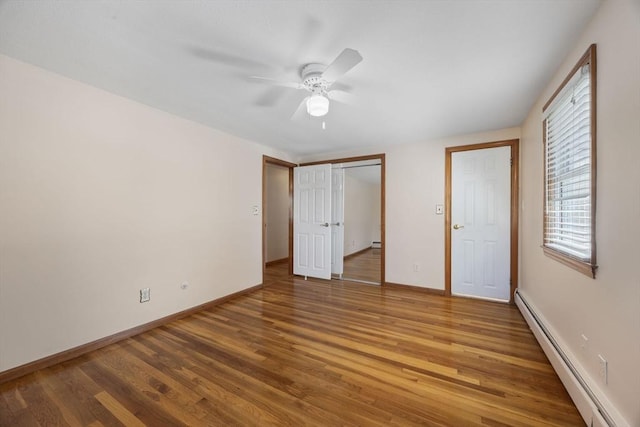 unfurnished bedroom featuring a baseboard radiator, wood finished floors, baseboards, a closet, and ceiling fan