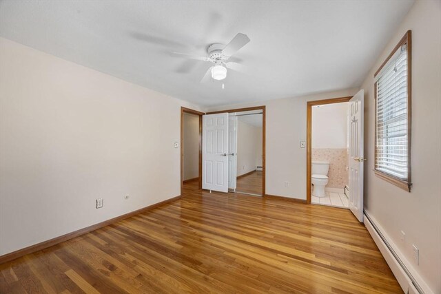 unfurnished bedroom featuring baseboard heating, light wood-style floors, a baseboard heating unit, and baseboards