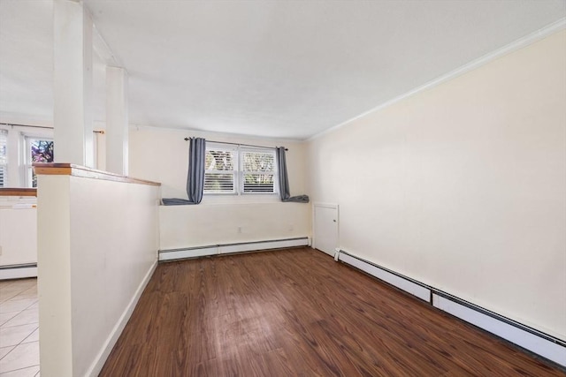 unfurnished room featuring a baseboard heating unit, crown molding, wood finished floors, and baseboards