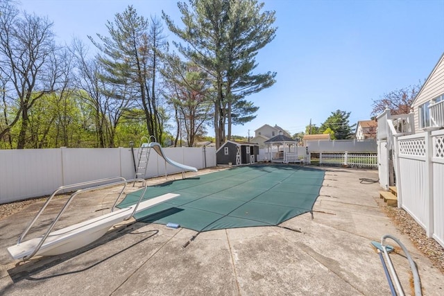view of pool featuring a water slide, a fenced backyard, a patio area, and a diving board