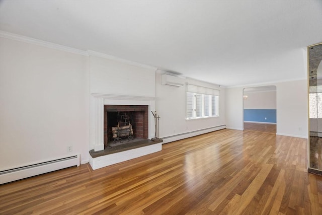 unfurnished living room with a baseboard heating unit, a wall mounted air conditioner, wood finished floors, crown molding, and baseboard heating