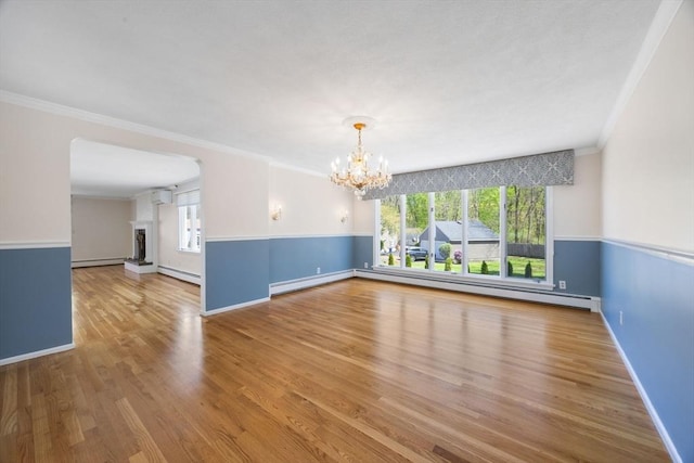 unfurnished dining area with baseboard heating, a chandelier, a baseboard heating unit, healthy amount of natural light, and ornamental molding