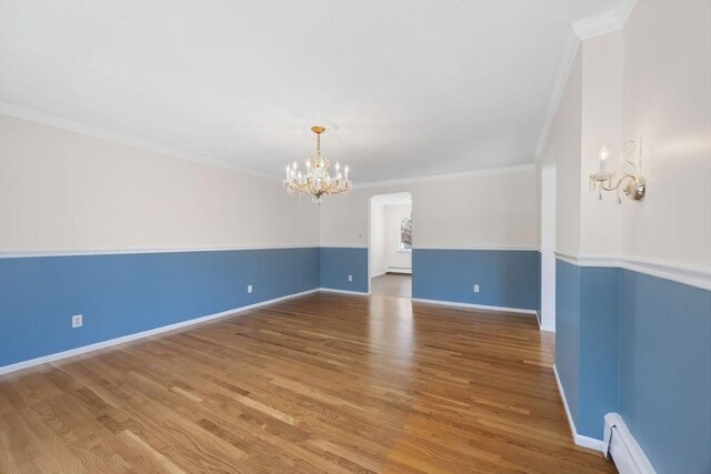 empty room with a chandelier, baseboard heating, wood finished floors, and ornamental molding