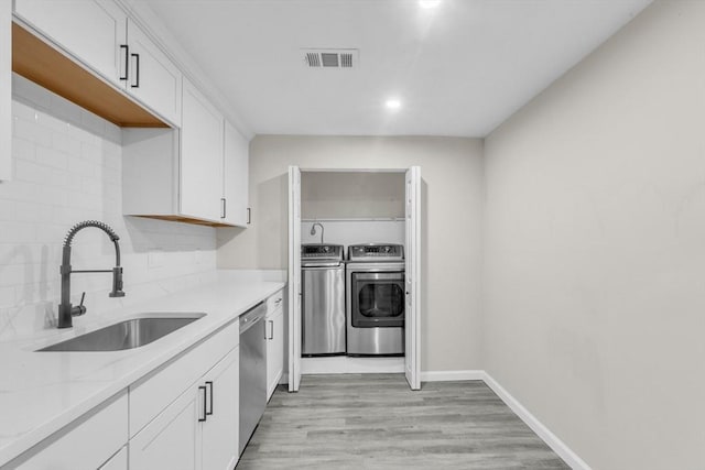 kitchen with sink, dishwasher, white cabinetry, tasteful backsplash, and washing machine and clothes dryer