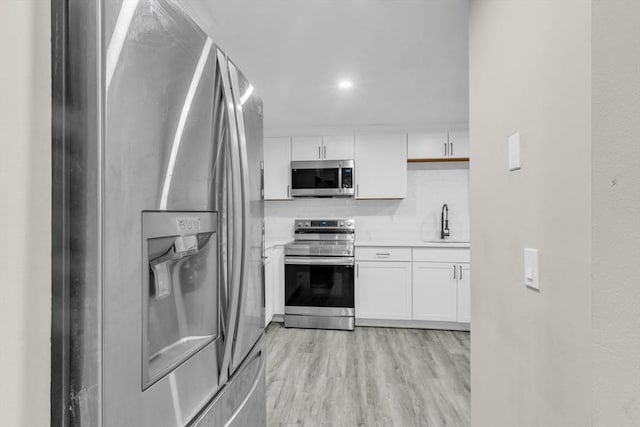 kitchen with sink, light hardwood / wood-style flooring, stainless steel appliances, and white cabinets