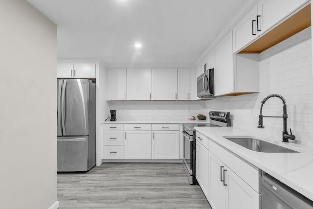 kitchen featuring sink, white cabinetry, light hardwood / wood-style flooring, stainless steel appliances, and light stone countertops