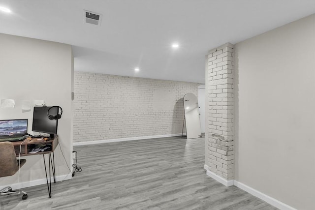 office space with brick wall and light hardwood / wood-style flooring