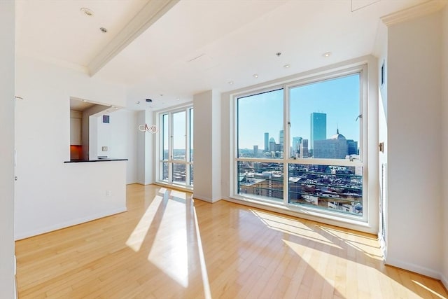 unfurnished living room with a wall of windows, light wood-type flooring, and ornamental molding