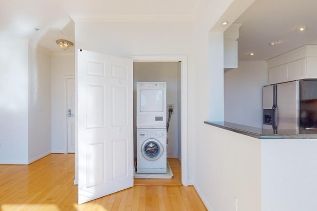 clothes washing area with stacked washer / dryer and light wood-type flooring