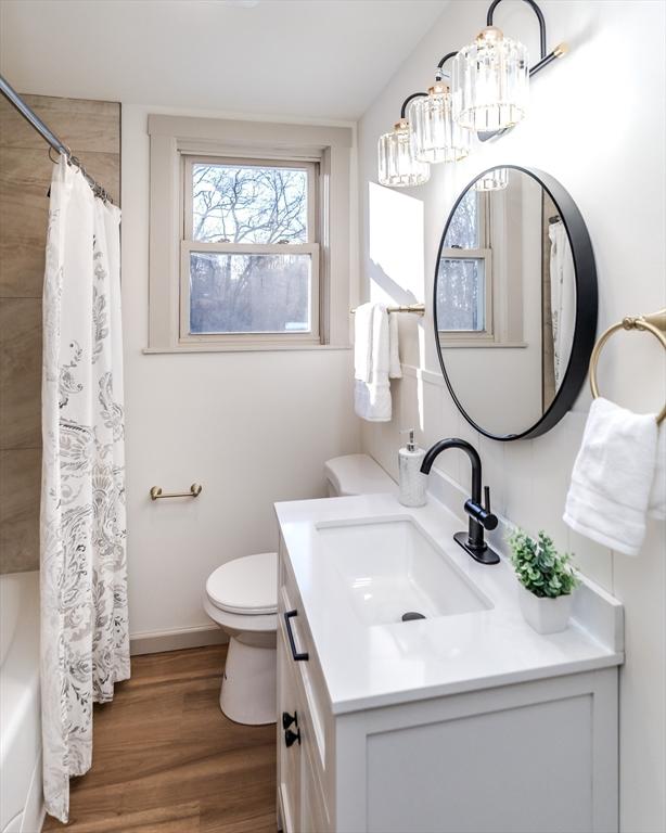 full bathroom with shower / tub combo, vanity, toilet, and hardwood / wood-style floors