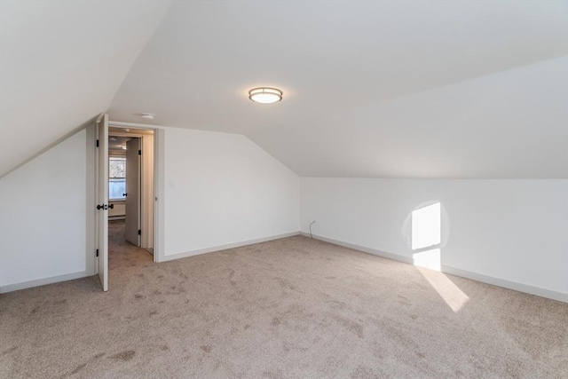 bonus room with vaulted ceiling and light colored carpet