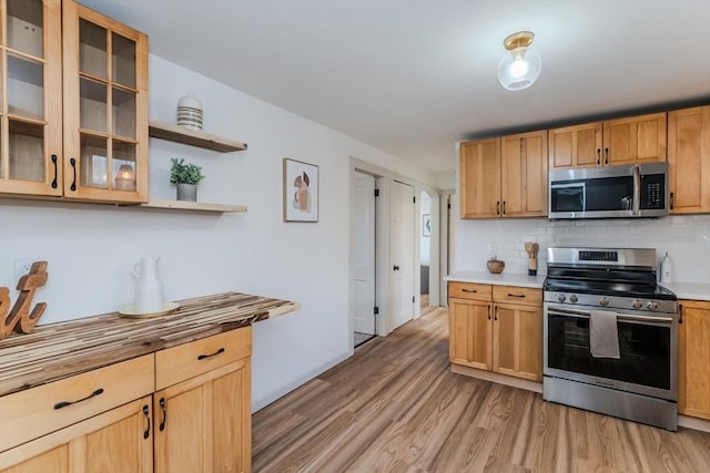 kitchen with stainless steel appliances, light hardwood / wood-style floors, and decorative backsplash