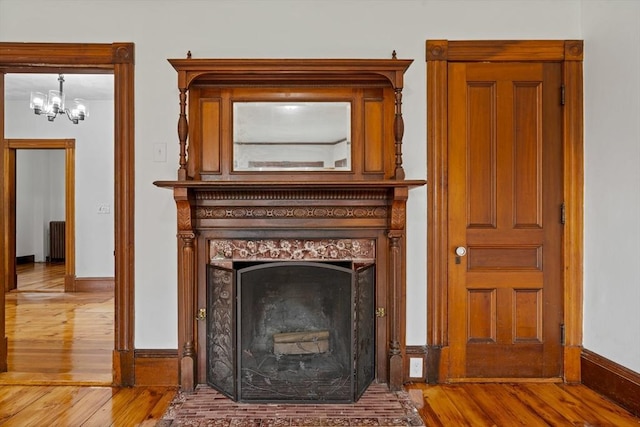 42 Middlesex St, Chelmsford, MA 01863 - detailed view of wood finished floors, radiator, a chandelier, baseboards, and a high end fireplace