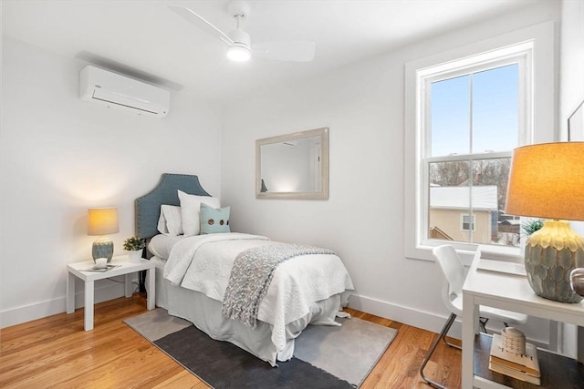 bedroom with light hardwood / wood-style floors, ceiling fan, and a wall unit AC