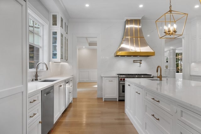 kitchen featuring appliances with stainless steel finishes, white cabinets, sink, and exhaust hood