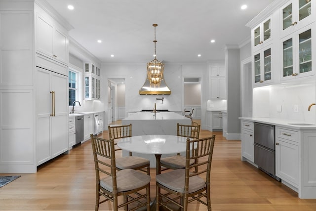 dining room featuring an inviting chandelier, sink, crown molding, and light wood-type flooring