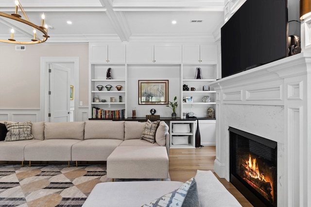 living room with hardwood / wood-style floors, beam ceiling, a high end fireplace, built in shelves, and coffered ceiling