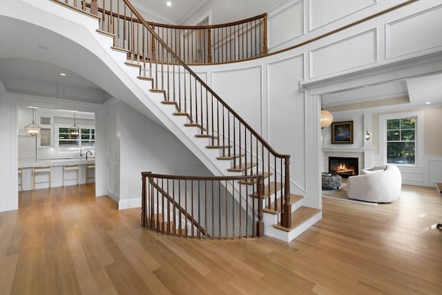 stairway featuring a towering ceiling, hardwood / wood-style flooring, ornamental molding, and plenty of natural light