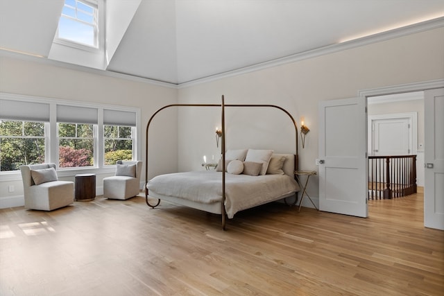 bedroom featuring light hardwood / wood-style floors, high vaulted ceiling, and a skylight