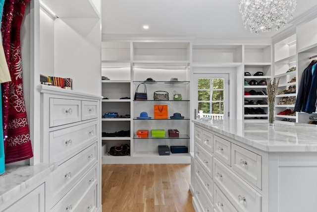 walk in closet featuring a notable chandelier and light hardwood / wood-style flooring