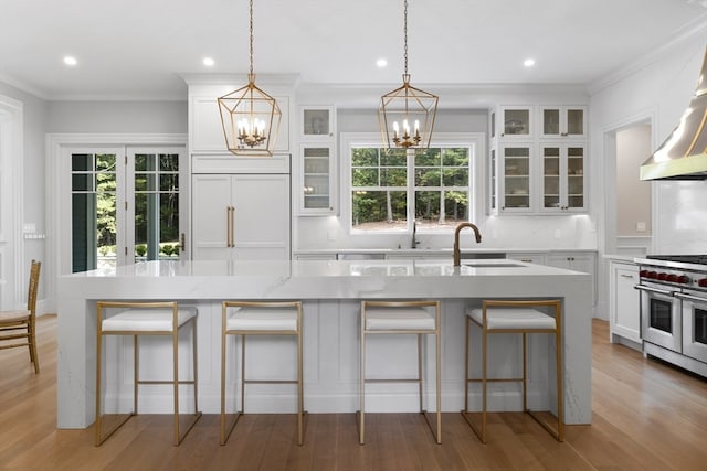 kitchen featuring light wood-type flooring, an island with sink, a kitchen breakfast bar, crown molding, and double oven range