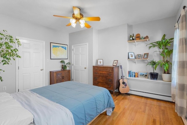 bedroom with ceiling fan, light hardwood / wood-style flooring, and a baseboard heating unit