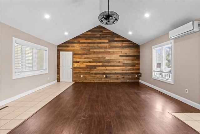 35 E Glen Dr, Westfield, MA 01085 - unfurnished living room with a wall mounted AC, wood walls, lofted ceiling, healthy amount of natural light, and wood finished floors