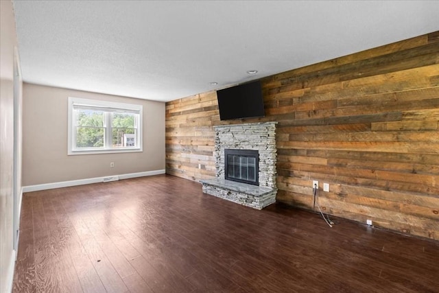 35 E Glen Dr, Westfield, MA 01085 - unfurnished living room featuring wooden walls, a stone fireplace, dark wood-type flooring, and baseboards
