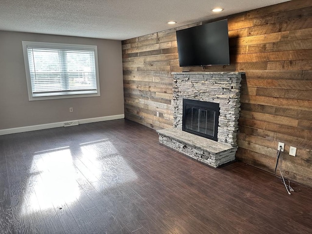 35 E Glen Dr, Westfield, MA 01085 - unfurnished living room featuring baseboards, a stone fireplace, dark wood-style flooring, a textured ceiling, and wood walls