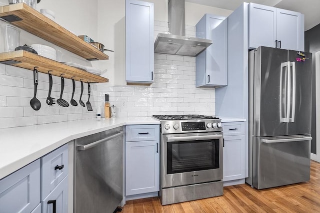 kitchen with open shelves, wall chimney exhaust hood, light wood-type flooring, and stainless steel appliances