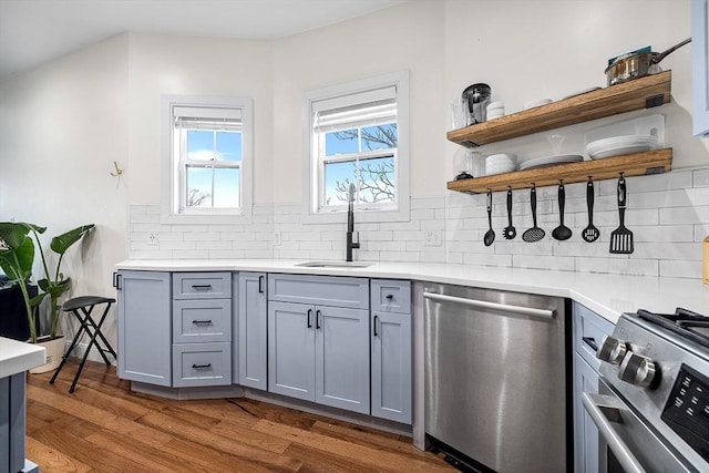 kitchen with light countertops, dark wood-style floors, gray cabinets, and appliances with stainless steel finishes