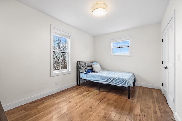 bedroom with light wood-type flooring, multiple windows, and baseboards