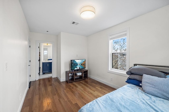 bedroom with visible vents, baseboards, and wood finished floors