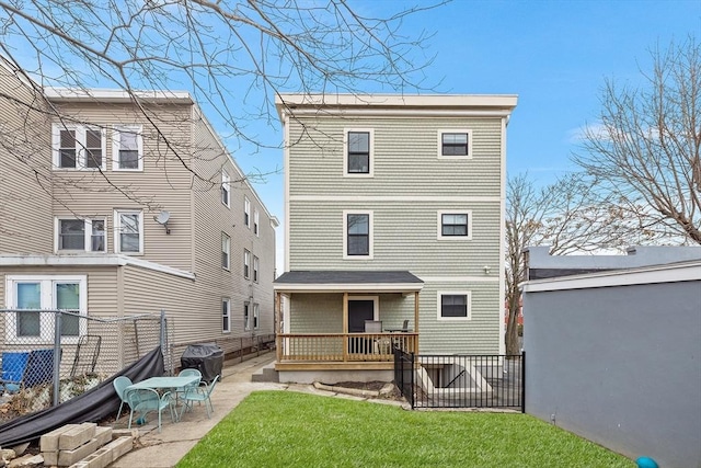 rear view of property featuring a patio area, a lawn, and fence