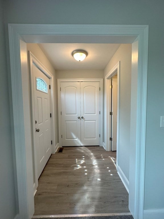 doorway to outside featuring baseboards and wood finished floors