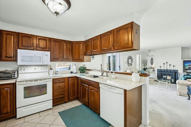 kitchen with a peninsula, white appliances, a sink, open floor plan, and light countertops