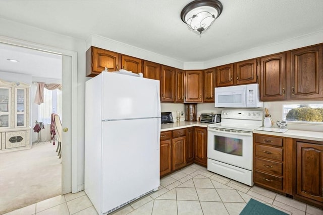 kitchen with brown cabinets, white appliances, light tile patterned floors, and light countertops