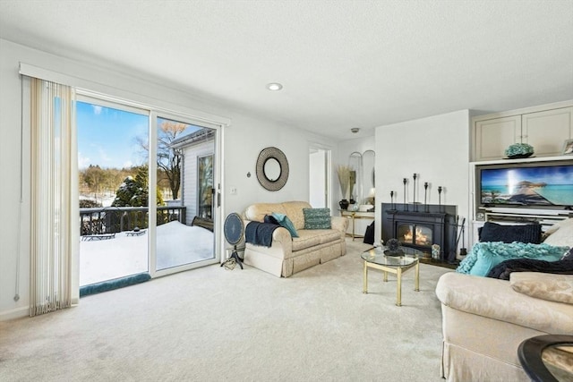 living room with recessed lighting, a glass covered fireplace, and light colored carpet