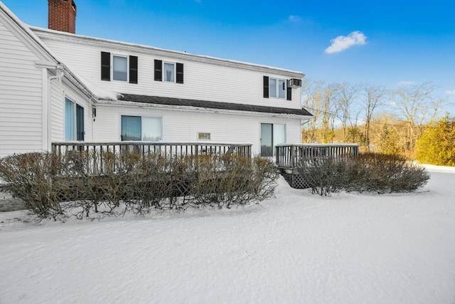 snow covered property featuring a chimney and a wooden deck