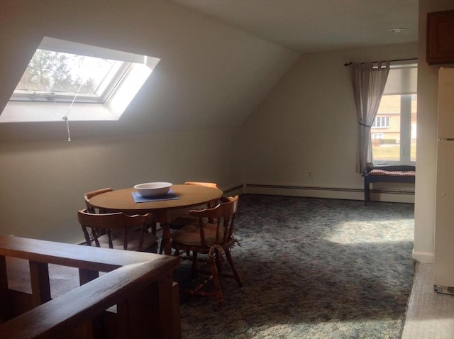 carpeted dining area with vaulted ceiling with skylight