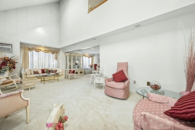 carpeted living area with a high ceiling, plenty of natural light, and a wall mounted air conditioner