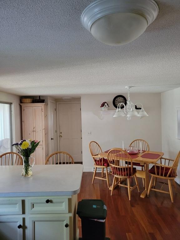 115 Captain Chase Rd, Yarmouth, MA 02664 - dining room featuring a textured ceiling, dark wood finished floors, a chandelier, and baseboards