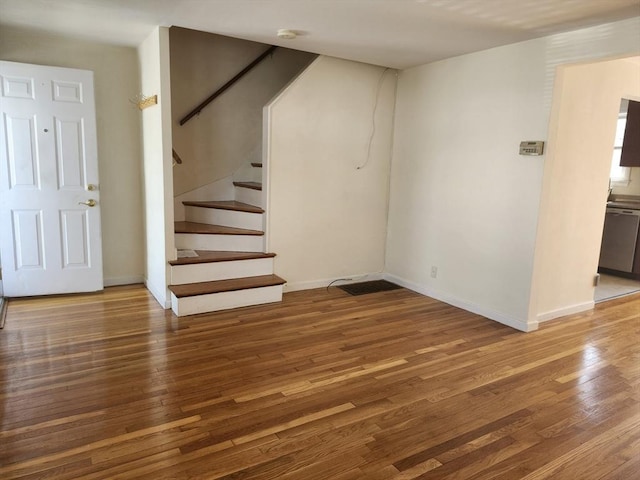 interior space featuring baseboards, wood finished floors, and stairway