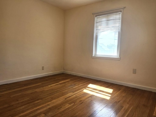 unfurnished room featuring baseboards and dark wood finished floors