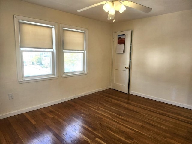 empty room featuring baseboards, ceiling fan, and dark wood-type flooring